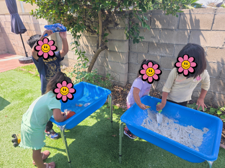 Children playing outside with sand boxes.